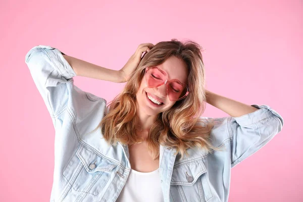 Joven hermosa mujer con gafas en forma de corazón sobre fondo rosa —  Fotos de Stock