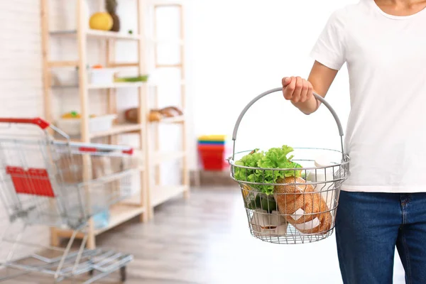 Femme avec panier plein de produits dans l'épicerie, gros plan — Photo