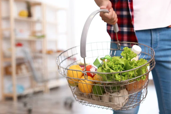 Homme avec panier plein de produits dans l'épicerie, gros plan — Photo