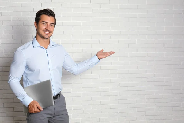 Joven profesor con portátil cerca de la pared de ladrillo. Espacio para texto —  Fotos de Stock