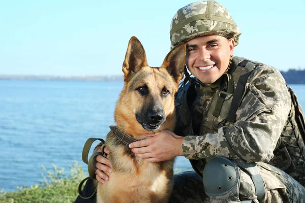 Mann in Militäruniform mit Schäferhund in Flussnähe — Stockfoto