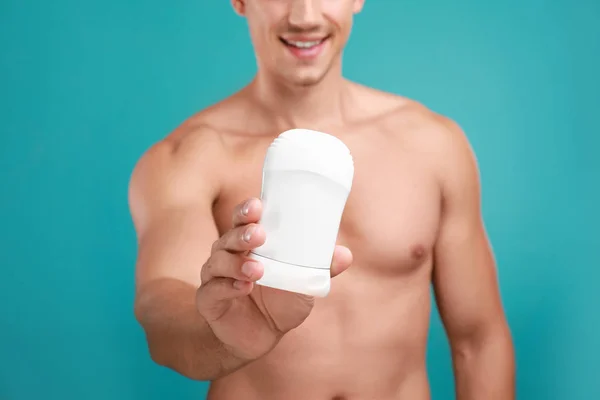 Jeune homme avec déodorant sur fond bleu clair, gros plan — Photo