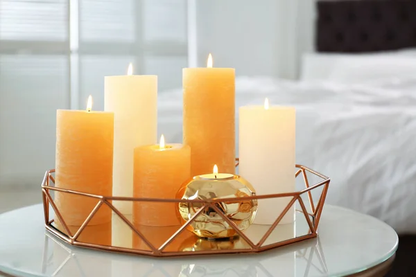 Złota taca z płonących świec na stole w sypialni — Zdjęcie stockowe