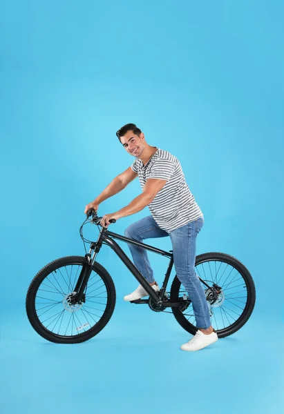 Pohledný mladý muž s moderním bicykl na světle modrém pozadí — Stock fotografie