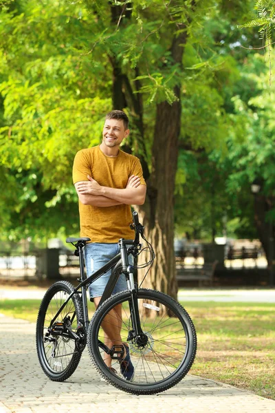 Красивий чоловік з сучасним велосипедом у парку — стокове фото