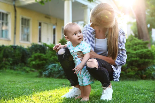 Teen nounou avec mignon bébé sur herbe verte à l'extérieur — Photo