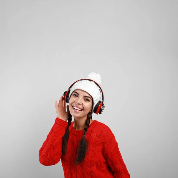 Mujer joven escuchando música con auriculares sobre fondo gris — Foto de Stock