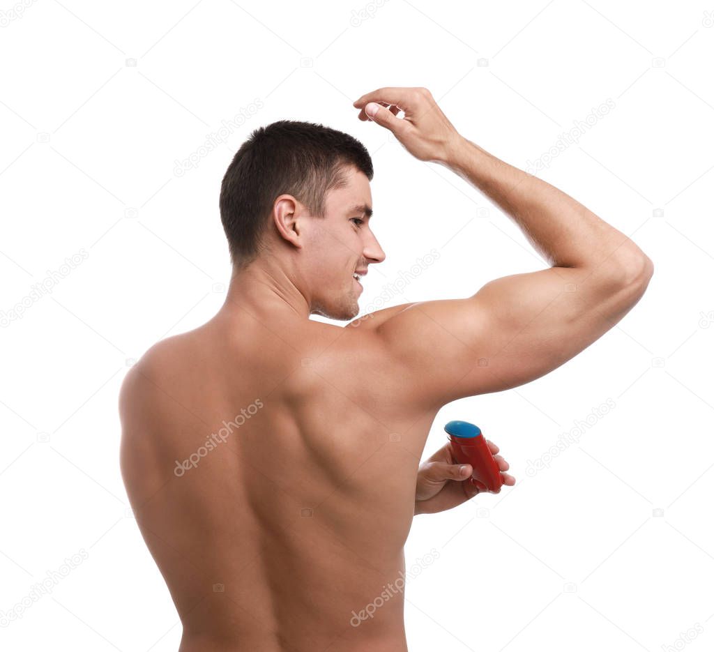 Young man applying deodorant to armpit on white background