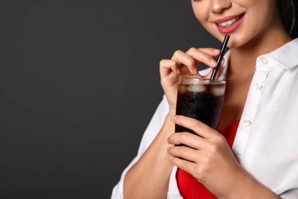 Young woman holding glass of cola on black background, closeup with space for text. Refreshing drink — Stock Photo, Image