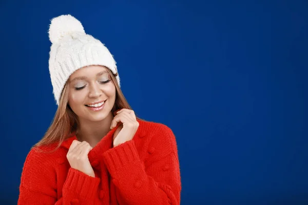 Jovem mulher em suéter quente e chapéu no fundo azul, espaço para texto. Temporada de Inverno — Fotografia de Stock