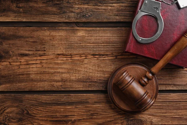 Плоская композиция с наручниками и молотком на деревянном столе, место для текста. Уголовное право — стоковое фото