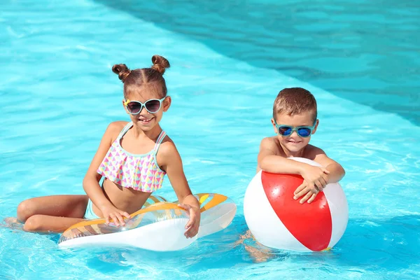 Schattige kleine kinderen met opblaasbaar speelgoed in het zwembad — Stockfoto