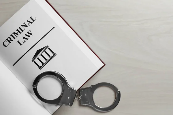 Criminal Law book and handcuffs on white wooden background, top view. Space for text — Stock Photo, Image