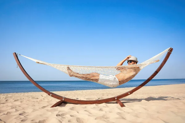 Giovane uomo rilassante in amaca sulla spiaggia — Foto Stock