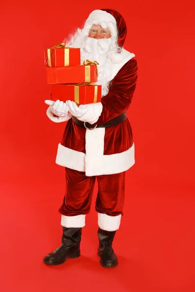 Auténtico Santa Claus con cajas de regalo sobre fondo rojo — Foto de Stock