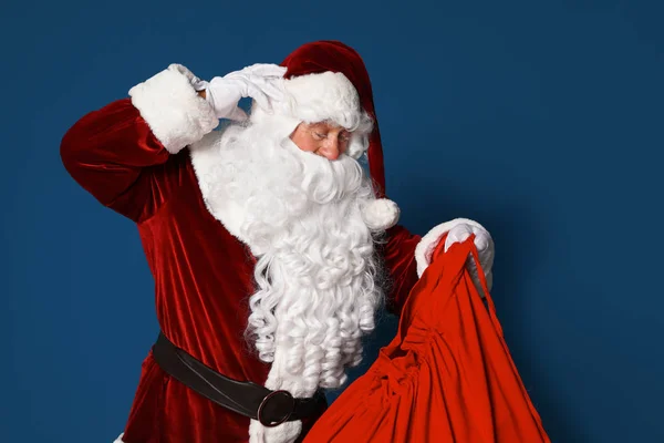 Настоящий Санта-Клаус с сумкой, полной подарков на синем фоне — стоковое фото