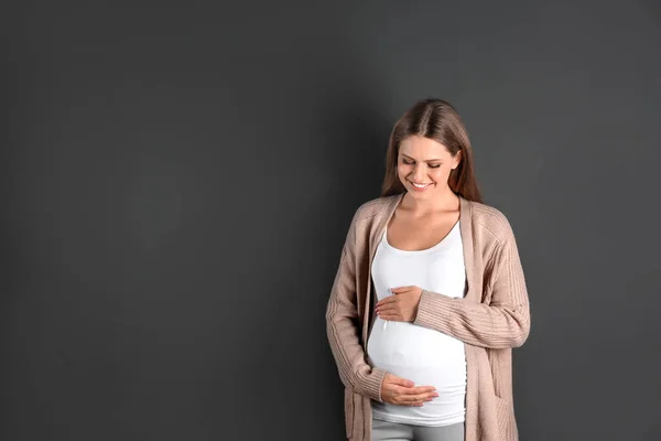Jonge zwangere vrouw op grijze achtergrond. Ruimte voor tekst — Stockfoto