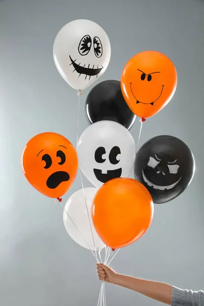 Donna che tiene palloncini di colore per la festa di Halloween su sfondo grigio chiaro, primo piano — Foto Stock