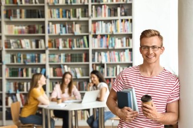 Kütüphanede kitap ve içki içen genç bir adam. Metin için alan