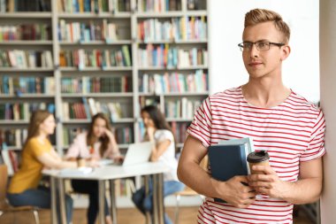 Kütüphanede kitap ve içki içen genç bir adam. Metin için alan