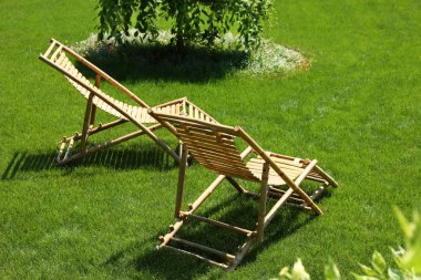 Güneşli günde güzel bahçede Ahşap şezlonglar