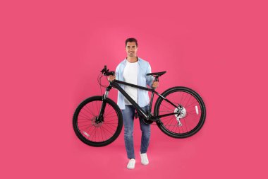 Pembe arka plan üzerinde modern bisiklet ile Yakışıklı genç adam