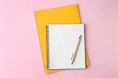 Dizüstü bilgisayarlar ve pembe arka plan üzerine kalem, üst görünüm