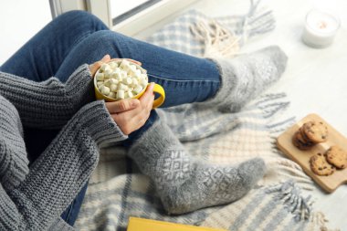 Pencere eşik, closeup oturan sıcak kakao fincan ile kadın. Kış içeceği