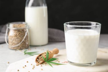 Siyah arka planda, ışık masasının üzerinde kenevir sütü bulunan kompozisyon. Metin için boşluk