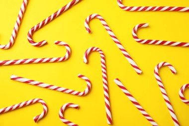 Flat lay composition with candy canes on yellow background