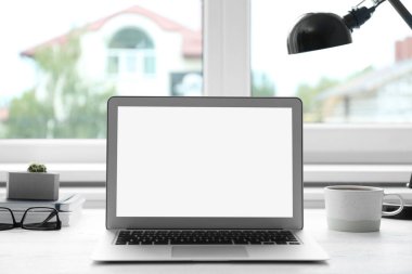 Evde pencere yakınında masada modern dizüstü bilgisayar