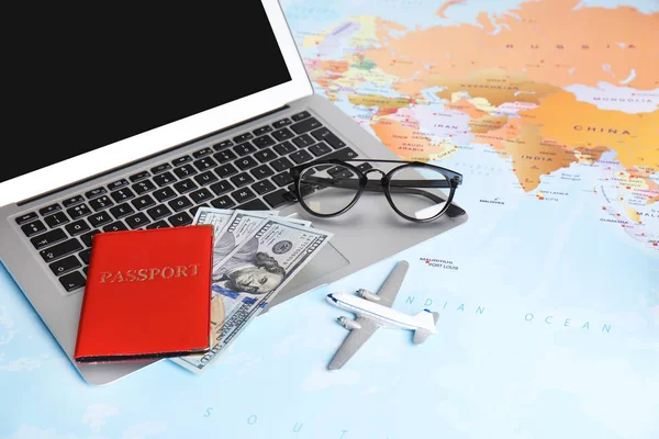 Kompozycja z laptopem, samolotem zabawkowym, pieniędzmi i paszportem na mapie. Biuro podróży — Zdjęcie stockowe