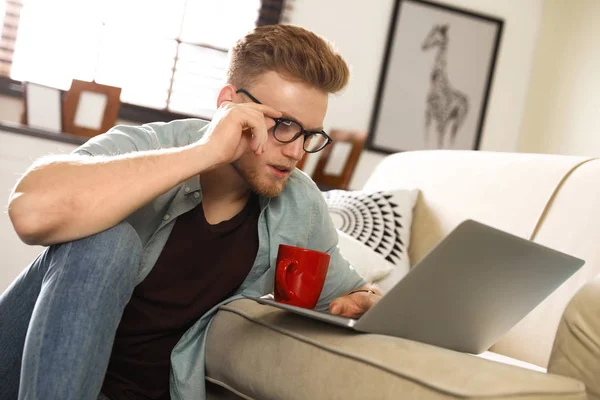 Genç adam oturma odasında dizüstü bilgisayar kullanıyor. — Stok fotoğraf