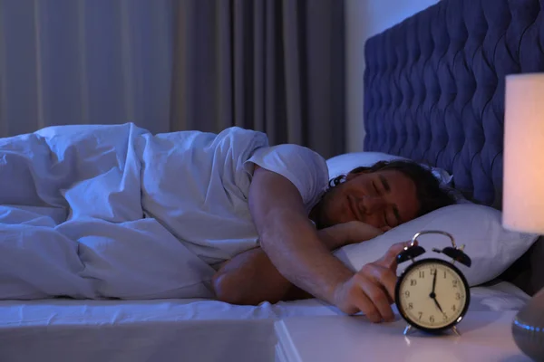 졸린 젊은 남자 는 나이트 스탠드에 알람 시계를 해제. 취침 — 스톡 사진