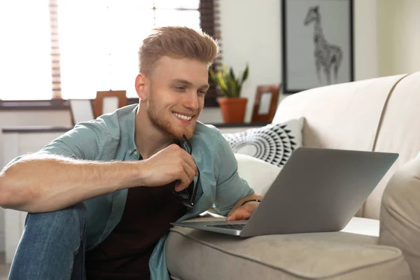 Genç adam oturma odasında dizüstü bilgisayar kullanıyor. — Stok fotoğraf