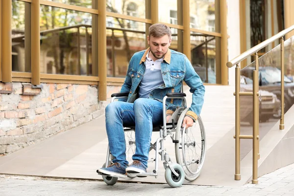 Jonge man in rolstoel met oprit bij gebouw buitenshuis — Stockfoto