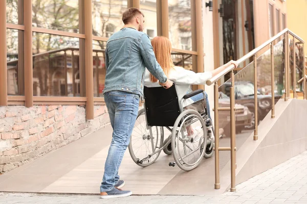 Kobieta na wózku inwalidzkim i mężczyźnie przy użyciu rampy na zewnątrz — Zdjęcie stockowe