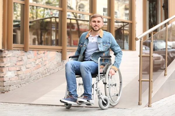 Young man in wheelchair using ramp at building outdoors — Stock Photo, Image