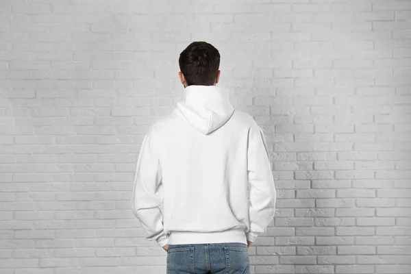Tuğla duvarda süveter giyen genç bir adam. Tasarım için alay — Stok fotoğraf