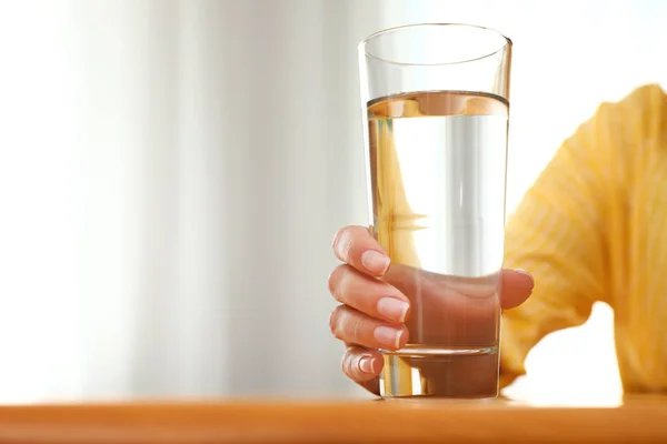 Woman holding glass of water at wooden table, closeup with space for text. Refreshing drink — Stock Photo, Image