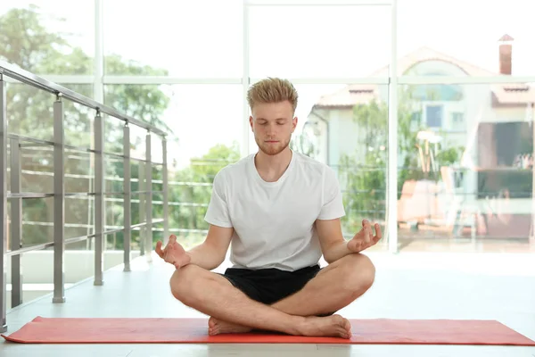 Guapo joven practicando yoga zen en interiores — Foto de Stock