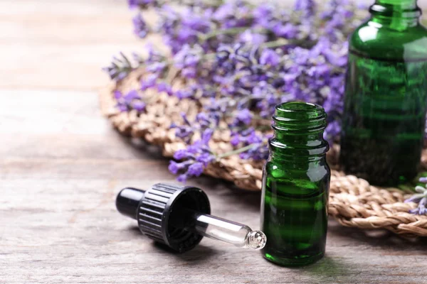 Botellas de aceite esencial y flores de lavanda sobre mesa de madera — Foto de Stock