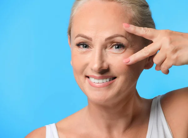Portrait of beautiful mature woman with perfect skin on light blue background — Stock Photo, Image
