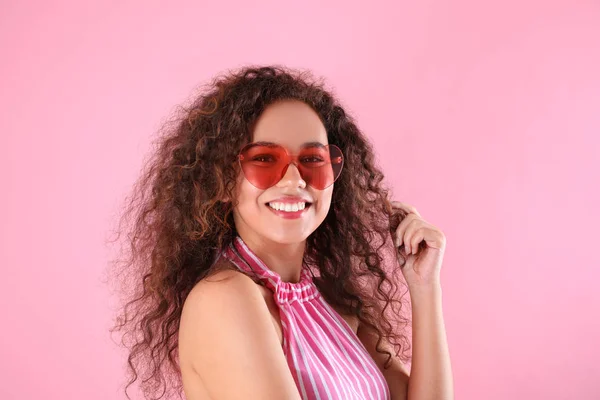 Młoda piękna African-American kobieta nosi okulary w kształcie serca na różowym tle — Zdjęcie stockowe