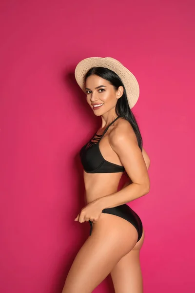 Hermosa joven en bikini negro con sombrero sobre fondo rosa —  Fotos de Stock