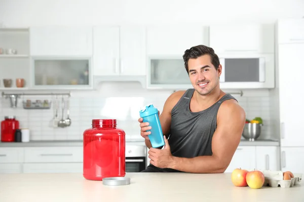 Hombre atlético joven con ingredientes para batido de proteínas en la cocina, espacio para el texto —  Fotos de Stock