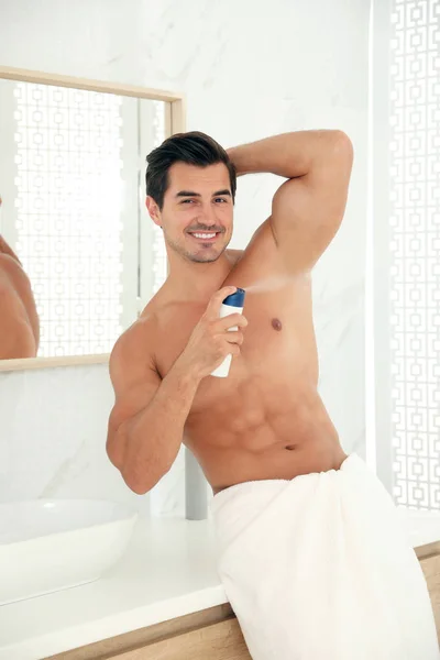 Bonito jovem aplicando desodorizante no banheiro — Fotografia de Stock