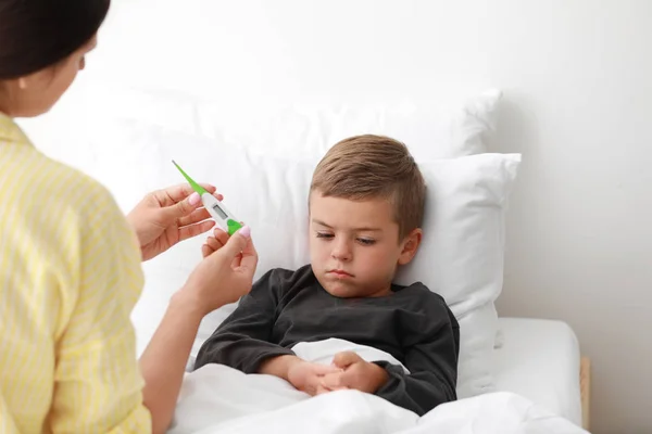 Moeder meettemperatuur van haar zieke zoon in bed — Stockfoto