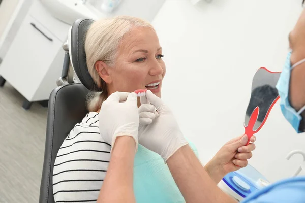 Dentista profesional que muestra la cubierta dental del paciente en la clínica — Foto de Stock