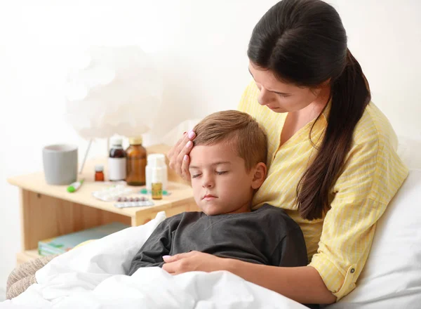 Mère prenant soin de son petit fils souffrant de froid au lit — Photo